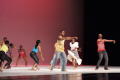 Photograph: [Photograph of nine individuals performing a dance on stage]
