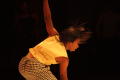 Photograph: [Photograph of a closeup of a dancer bending down to touch the stage]