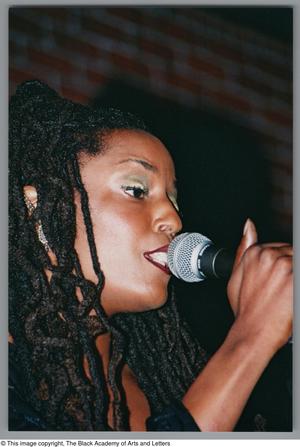 Primary view of object titled '[Photograph of soul artist Rhea singing into a microphone]'.