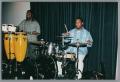 Photograph: [Photograph of two men playing their respective drums on stage]