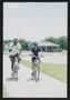 Photograph: [Two cyclists smiling as they ride into a playground park: Lone Star …