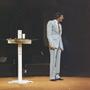Photograph: [Televangelist Mike Evans giving a sermon in a grey suit]