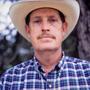 Photograph: [Portrait of an older man in a cowboy hat and plaid shirt]