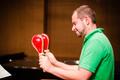 Photograph: [A man in a green shirt holding two red maracas]