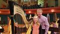 Photograph: [A man and a girl posing next to a harp onstage]