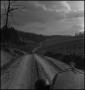 Photograph: [An automobile driving down a dirt road]