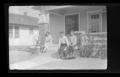 Photograph: [Irene Williams sitting on a front porch with her children]