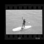 Photograph: [Girl standing on a surfboard at a lake]