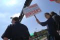 Primary view of [Woman holding large placard next to police officer]