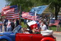 Photograph: [Protesters riding in red, white and blue Volkswagen Beetle]