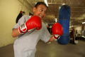 Primary view of [Boy in red boxing gloves in front of blue heavy bag]