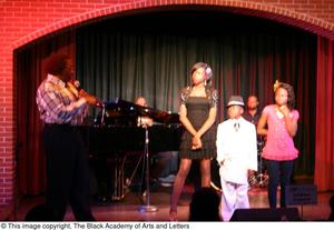[Kirondria Woods, Rachel Webb, boy in white suit, and Curtis King standing on stage]