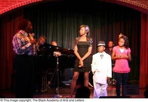 [Kirondria Woods, Rachel Webb, boy in white suit, and Curtis King standing on stage]