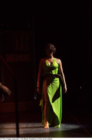 [Performer in green dress in spotlight]