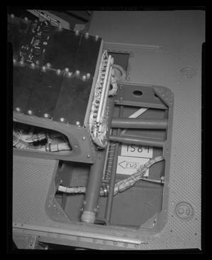 [Photograph of tubing and wires inside the floor of the cockpit of a UH-1B Iroquois helicopter]