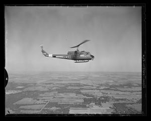 [Photograph of a UH-1E Iroquois helicopter flying high over pastures, 5]