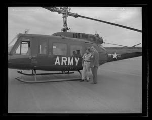[Photograph of two men standing outside a YUH-1B Iroquois helicopter]