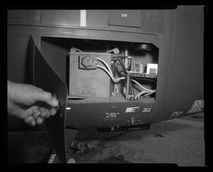 [Photograph of a hand opening an exterior compartment door on a UH-1E Iroquois helicopter]