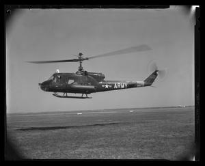 [Photograph of a UH-1B Iroquois helicopter hovering over a field]
