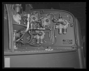 [Photograph of mechanical components and flexible tubing inside a UH-1B Iroquois helicopter]