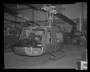 [Photograph of a UH-1C Iroquois helicopter and another aircraft in an interior space]