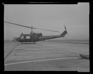 [Photograph of a side view of a UH-1B Iroquois helicopter parked on a concrete surface]