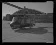 Primary view of [Photograph of a UH-1B Iroquois helicopter parked outside an American Airlines building]