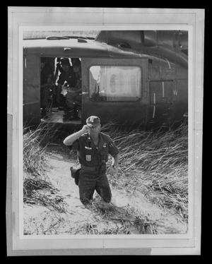 [Photograph of a soldier standing in a marsh outside a UH-1A Iroquois helicopter]