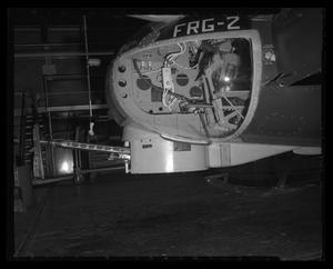 [Photograph of a closeup of the nose of a UH-1B Iroquois helicopter in an indoor space]