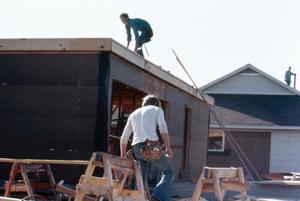 [Two men doing construction on a home]