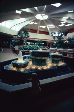 [Child in front of a mall fountain]