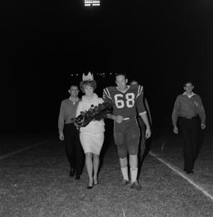 [Football player walking with a woman]