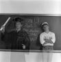 Photograph: [student by chalkboard in regalia]
