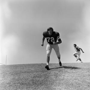 [Football player #72, K. O'Neil, jogging down a inclined grass field with #33 in the background]