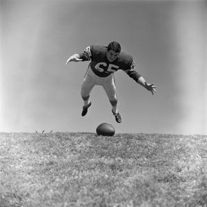 [Football player #65, John Edwards, above a grounded ball]