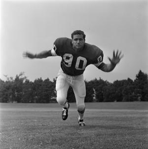 [Football player #90 from the 1971 season charging the camera with arms extended out to the side]