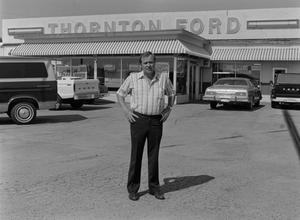 [Howard Thornton standing in front of a Ford dealership]