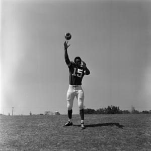 [Football player #15, George Woodrow, stands and throws a football]