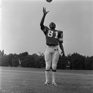 [Football player #81 from the 1971 season standing squarely with his right hand reaching up for a football]