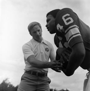 [Football coach standing with a player]