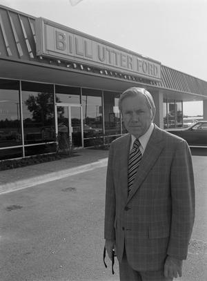 [Man smiling in front of a Ford dealership, 5]
