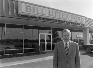 [Man smiling in front of a Ford dealership, 3]
