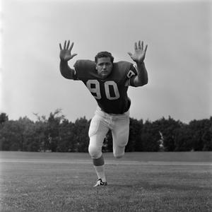 [Football player #90 from the 1971 season charging the camera with palms held forward]