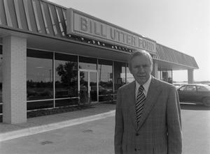 [Man smiling in front of a Ford dealership, 2]