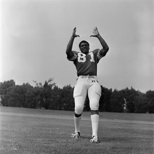 [Football player #81 from the 1971 season standing with his arms raised together and hands open]