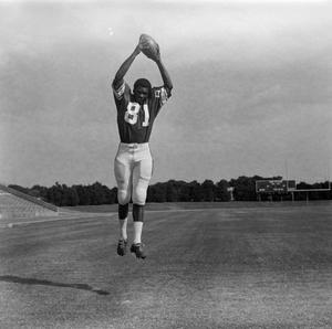 [Football player #81 jumping to catch a football framed by a stadium field, 2]