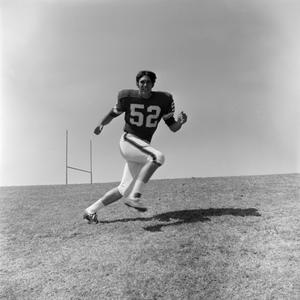 [Football player #52 Jerry Robinson running across an inclined field]