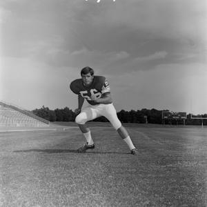 [Football player #56, George Bray, moving to the left framed by a flat stadium field]