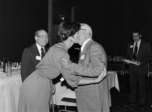 [Young woman kissing older man on the cheek at ceremony]