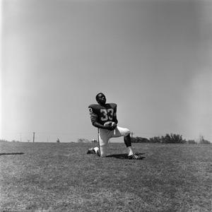 [Football player #33, Carl Hayes, on one knee holding a football]